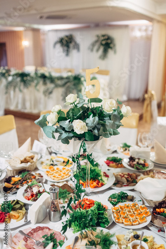 Rich served dinner table decorated with white roses and green branches