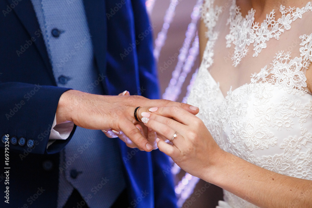 bride wearing the golden ring on finger of her husband