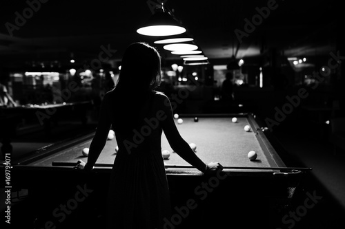 Photo Portrait of an attractive young woman in dress playing pool