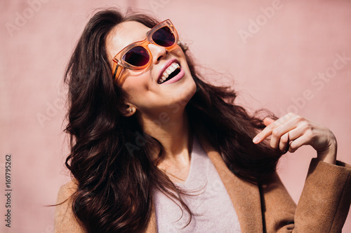 Smiling woman touches her hair posing in foxy sunglasses
