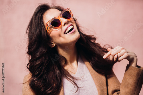 Smiling woman touches her hair posing in foxy sunglasses photo