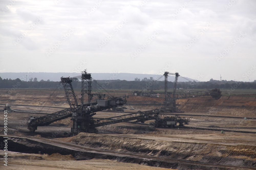 Germany, North Rhine Westphalia, -june 2017: ground excavator in action moving mullock and soil at open pit coal mine; Germany,for winning brown coal Germany, North Rhine Westphalia, -june 2017: ground excavator in action moving mullock and soil at open pit coal mine; Germany,for winning brown coal