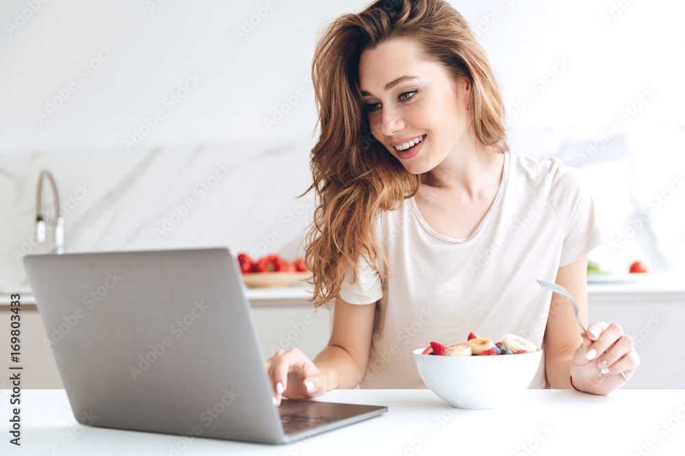 Pretty woman chatting on laptop and eating fruits Pretty woman chatting on laptop and eating fruits
