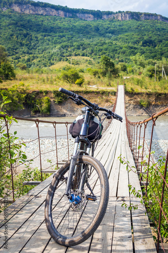 Bicycle on suspension cable bridge, Crossing the river. Adygea republic, Krasnodar region, Russia