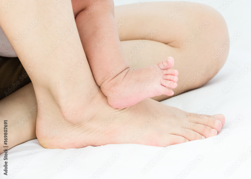 Baby and mother feet on a white floor