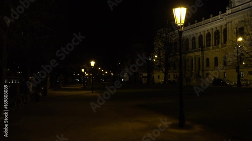 A lamplit path running alongside a river at night in an urban area photo