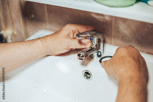 Fotografia Man repair and fixing leaky new faucet in bathroom