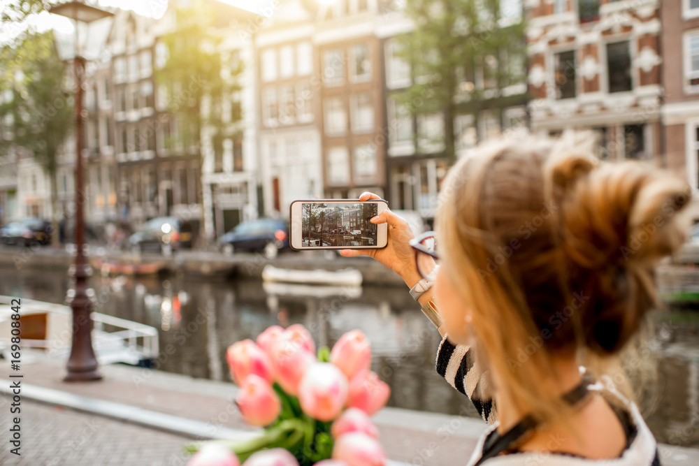 Fototapeta premium Woman photographing with phone beautiful cityscape during the morning in Amsterdam city