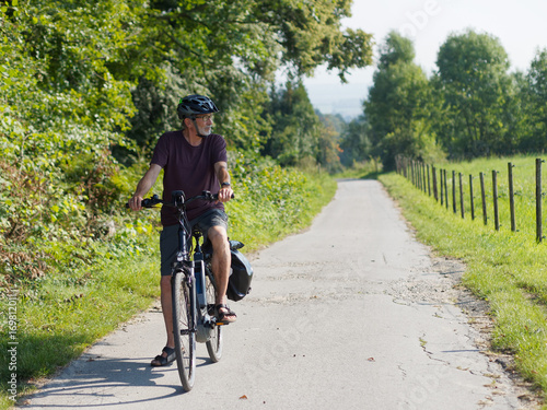 Älterer Mann macht Radtour mit E-Bike in schöner Landschaft