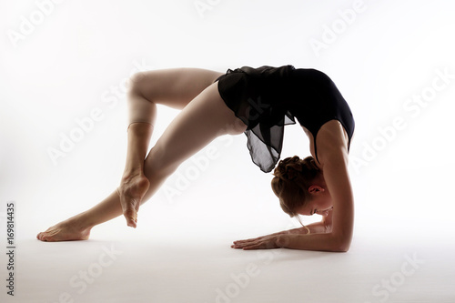 graceful dancer performs the deflection standing on the bridge silhouette on a light background