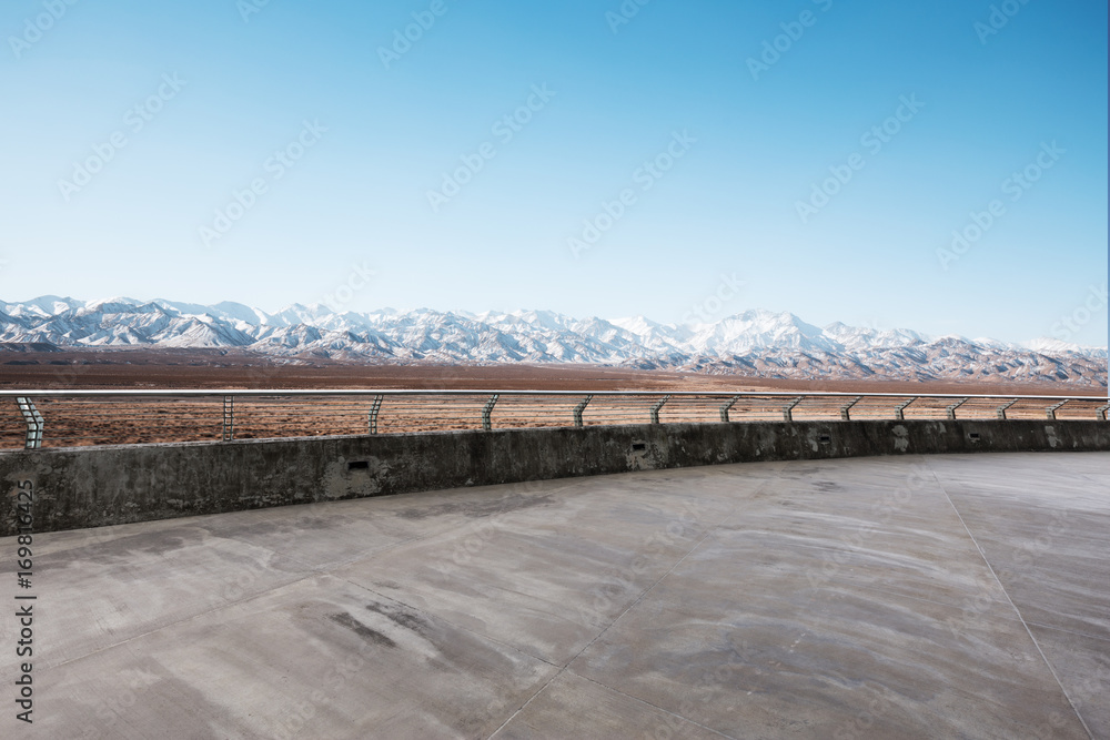 empty cement road with snow mountains in blue sky