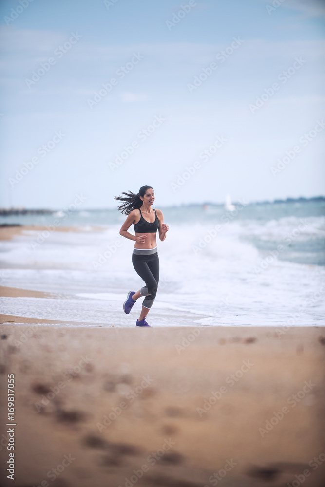 Beautiful young woman in sportswear runs on the beach Beautiful young woman in sportswear runs on the beach