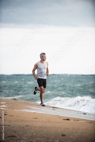 A man in sportswear is running on the beach