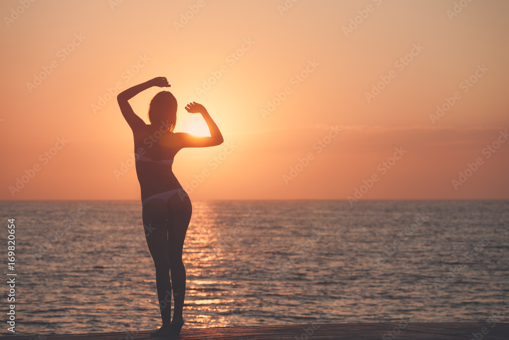 Beautiful woman silhouette over ocean sunrise background