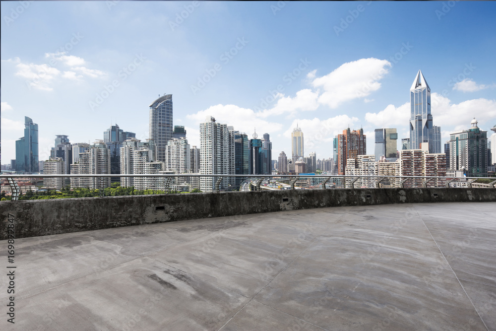 Fototapeta premium empty concrete road with cityscape of modern city in blue sky
