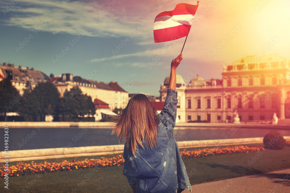 Fototapeta premium Young woman showing austrian flag in park vintage