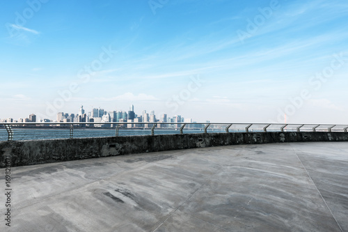 empty concrete road with cityscape of modern city in blue sky © zhu difeng
