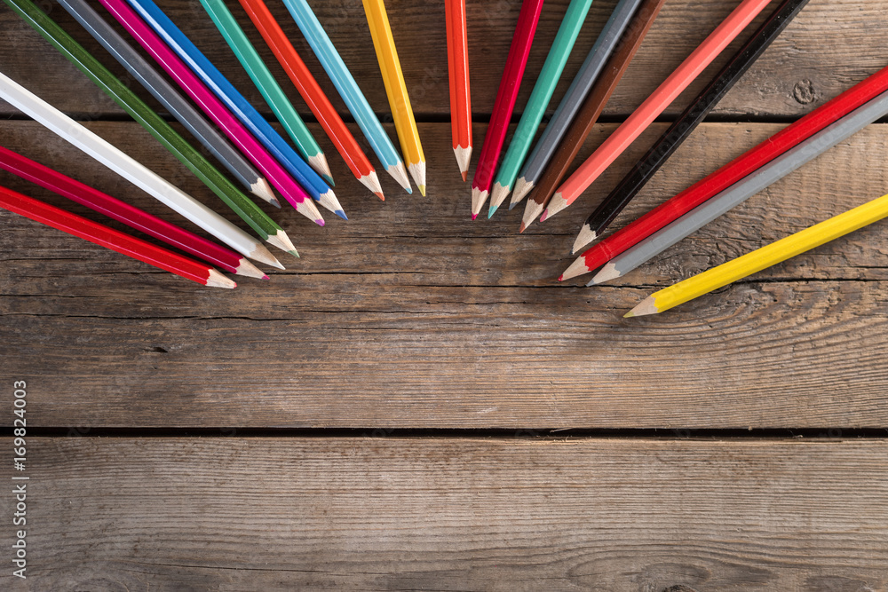 Fototapeta premium Back to school concept background with colored pencils on wooden table, flat lay