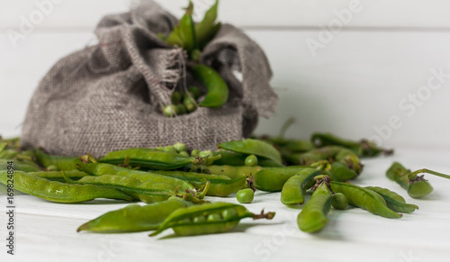 Fresh green peas on white textured wooden boards with a canvas bag beautiful background photo