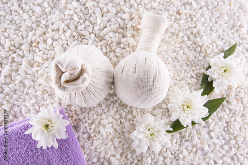 Spa. Still life. Herbal balls, a towel and flowers on a background of white pebbles.