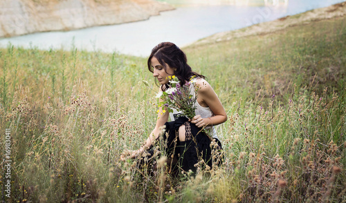 Giovane donna che raccoglie fiori selvatici in un prato di montagna photo