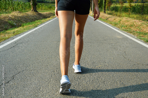 Young fitness woman legs running on asphalt road