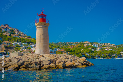 Fototapeta Naklejka Na Ścianę i Meble -  Beautiful view of Mallorca balearic islands, with a lighthouse and some buildings in the mountain in the horizon, with gorgeous blue water and a beautiful blue sky, in Spain