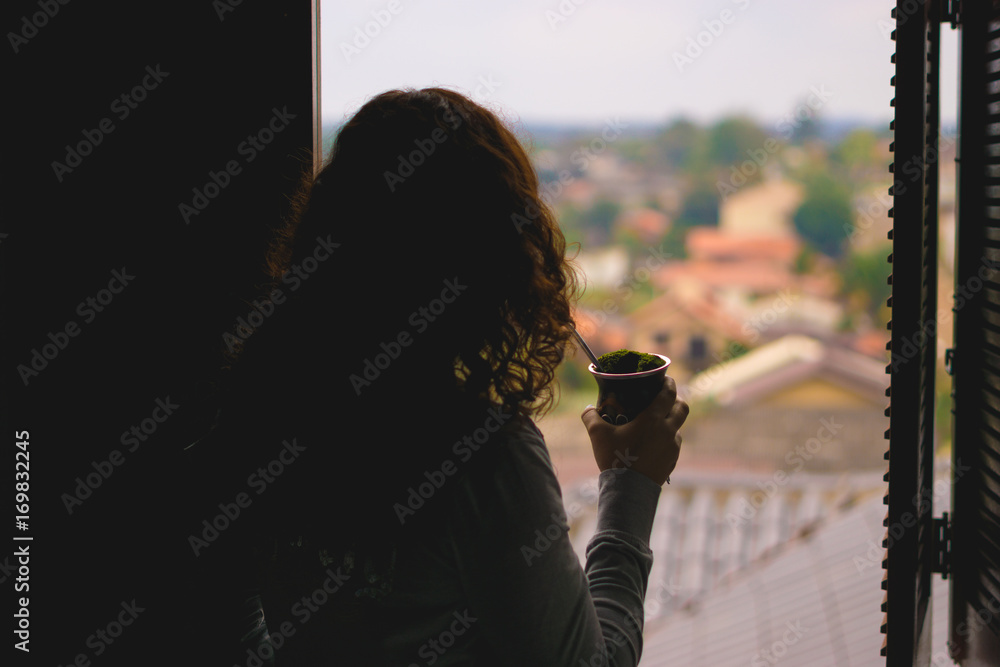 Woman watching the view from window drinking chimarrao - Rio Grande do Sul - Southern Brazil.