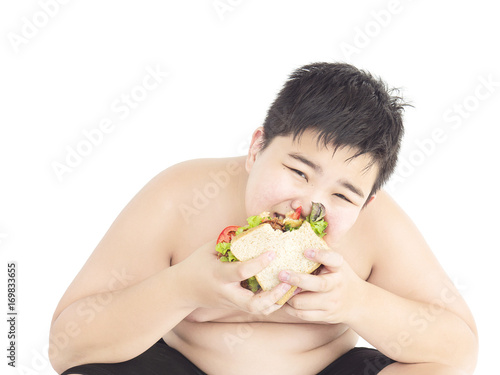 A fat boy is happily eating sandwich.