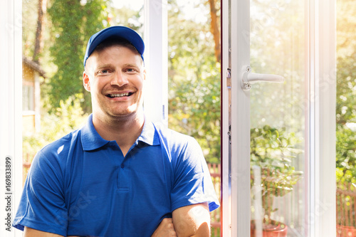 smiling window installer in blue uniform standing in the room