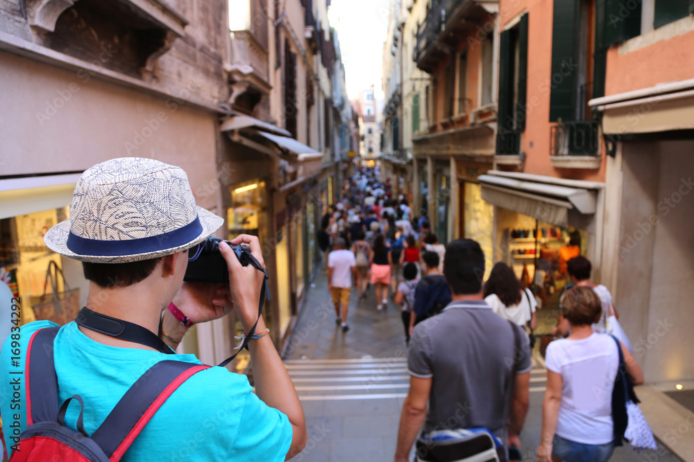 Young photographer takes a picture to people walking in the crow Young photographer takes a picture to people walking in the crow