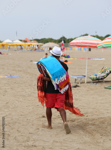 Abusive walker walking on the beach selling cotton fabrics