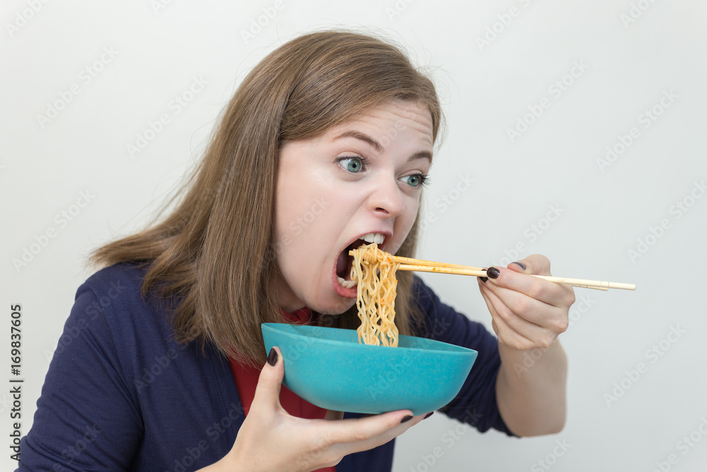Young caucasian girl eating noodles using chopsticks Young caucasian girl eating noodles using chopsticks