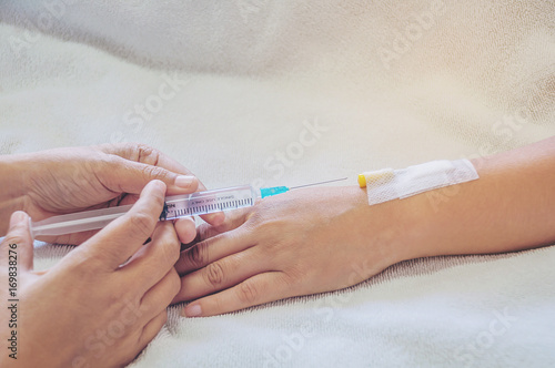 Doctor holding syringe in hand injects to a patient arm