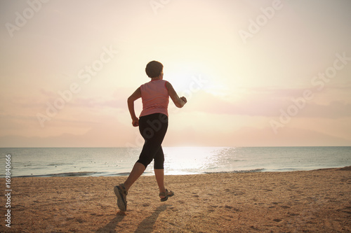 senior woman jogging on sea beach at the sunrise © capifrutta