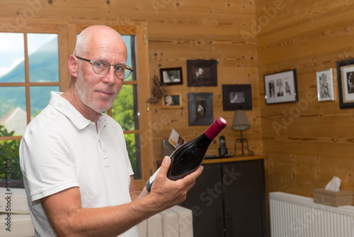 mature man with bottle of red wine, at home