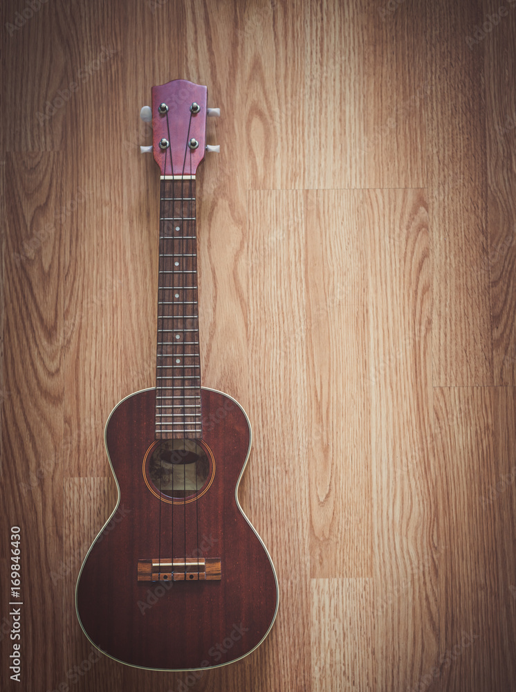 Naklejka premium Still Life Ukulele on Wooden Floor Background with Copy Space for Background