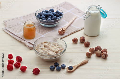 Breakfast of oatmeal with blueberries, raspberries, honey, milk and hazelnuts