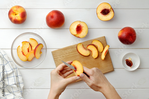 Step by step recipe galette or pie with nectarines. Female hands cut nectarines into slices for cake.