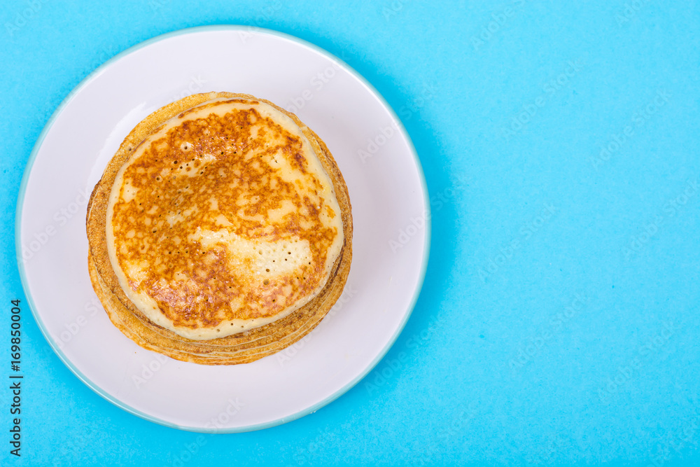 Stack of fresh delicious pancakes on white plate on blue backgro Stack of fresh delicious pancakes on white plate on blue backgro