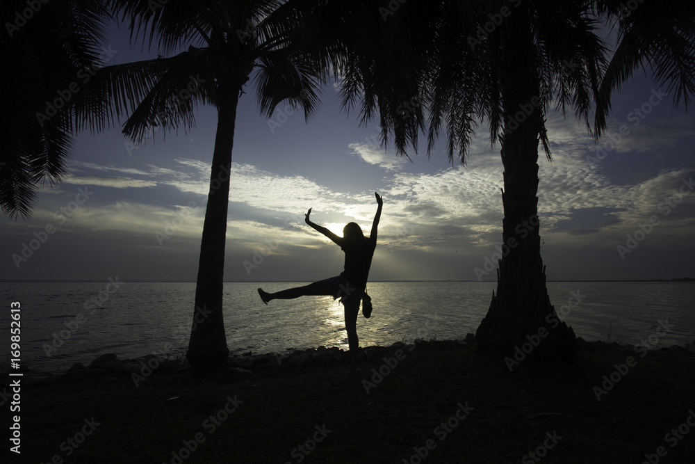 Silhouette of young woman, standing alone by the sea, fitness on the dam.