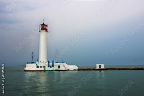 White lighthouse with a red tip in the sea.