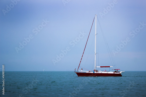 Yacht sailing at waves of the sea. Nautical landscape with sailboat - cruising yacht sailing under full sail taking part in regatta race. Yachting - maritime romantic trip on the yacht with red sails.
