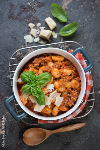 Tableau sur toile Potato gnocchi with meat sauce and parmesan cheese in a bowl, above view on a br