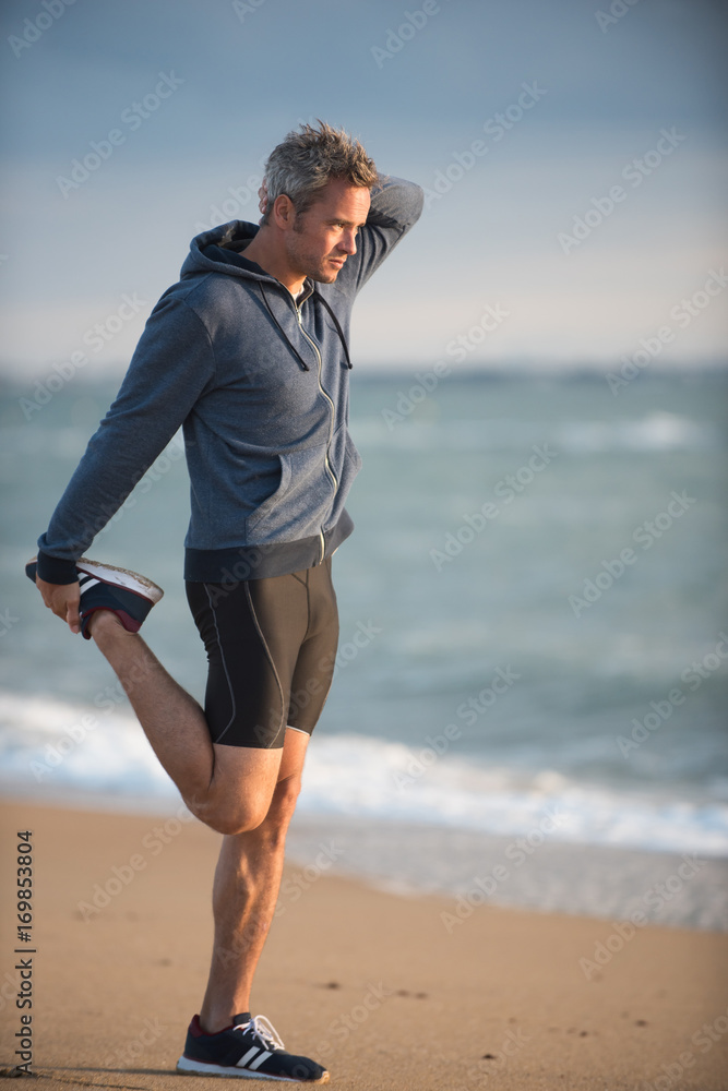 man doing stretches on the beach in the early morning man doing stretches on the beach in the early morning