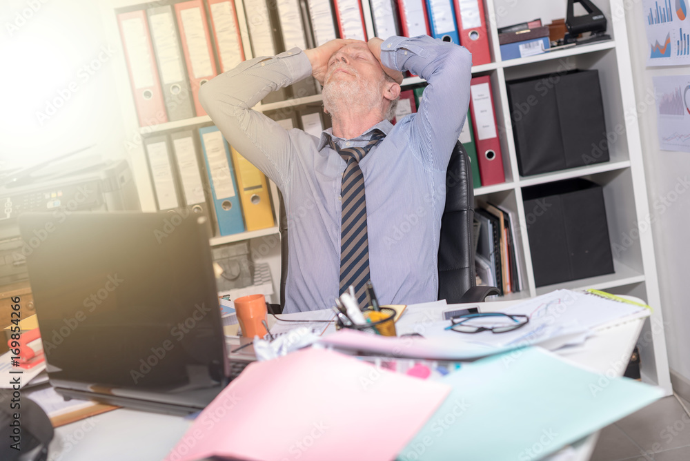 Overworked businessman sitting at a messy desk, light effect Overworked businessman sitting at a messy desk, light effect