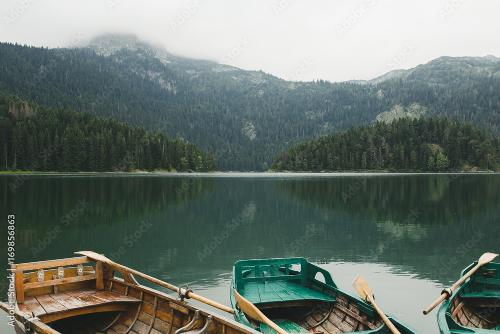Landscape photo of beautiful mountain lake with boats or kayaks in foreground