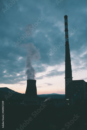 Silhouette of big thermal power plant chimneys photographed at night.