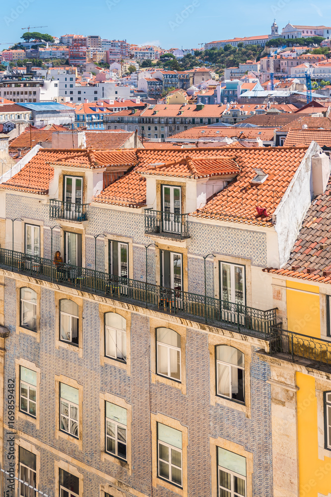      Orange tiles roofs in lisbon, Portugal, typical houses, woman on a balcony
