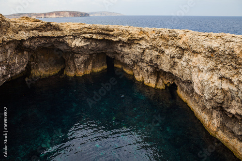 Limestone rocks of Malta coast. Hidden water cave.
